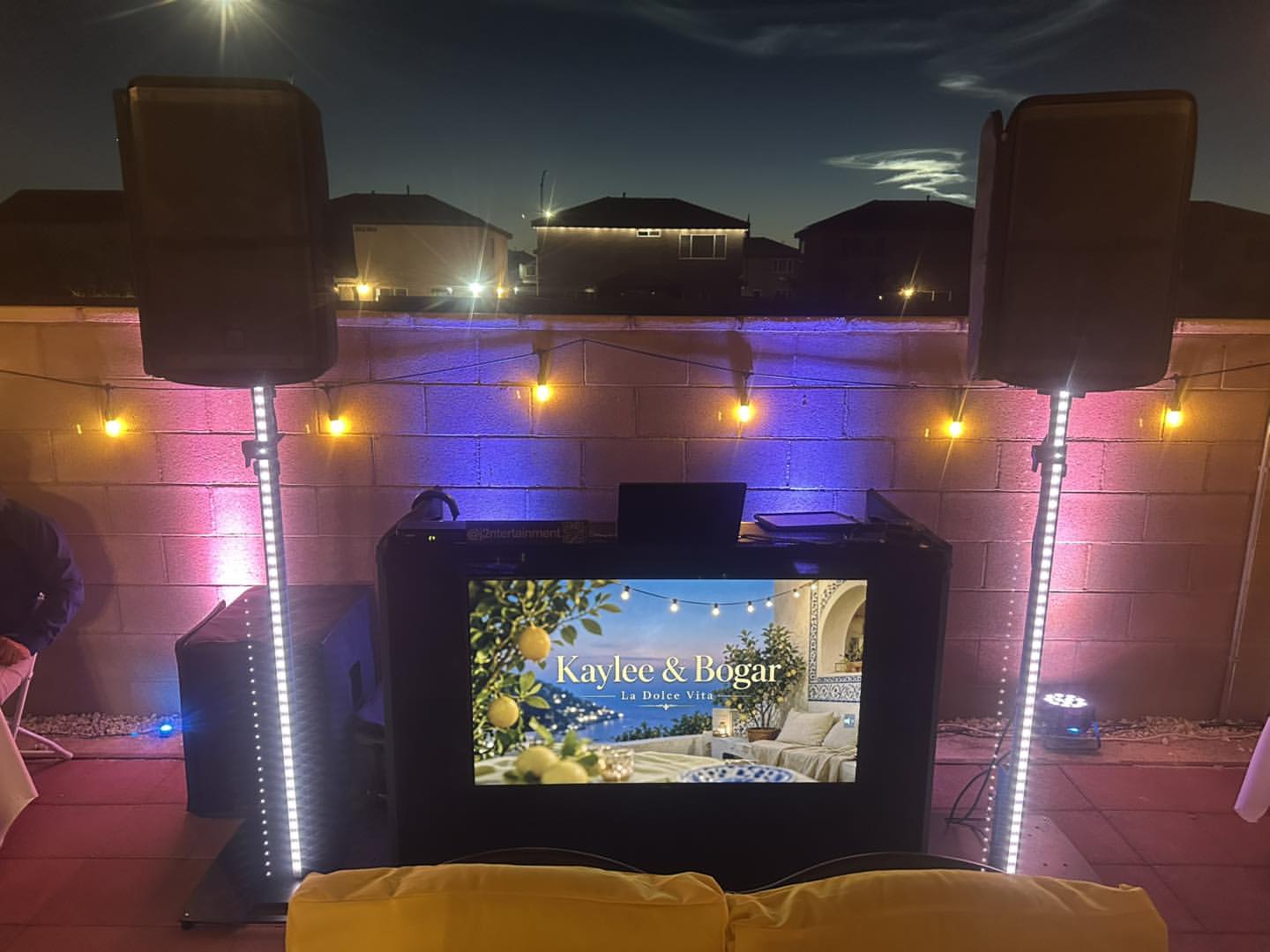 Smaller backyard booth with speakers, uplights, and a screen